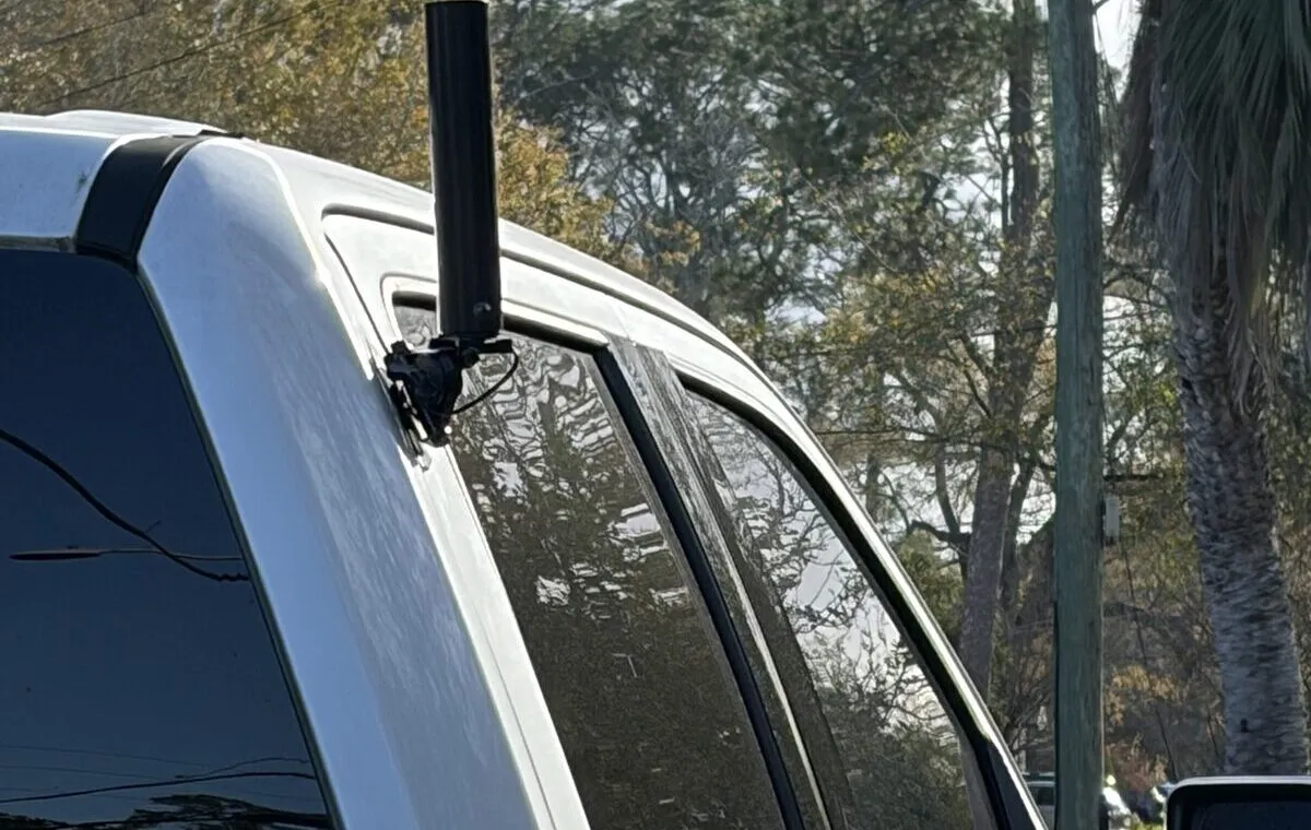 Passenger side of the white F-150 with a short black dual-band antenna on an NMO bracket at the top rear corner of the rear door.